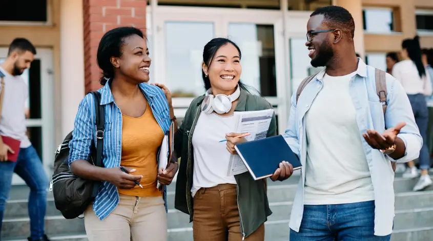 diverse young adults smiling outside a school building