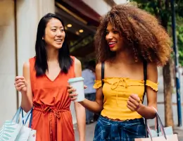 two women walking outside and holding shopping bags