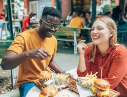 two friends eating hamburgers outside at a restaurant